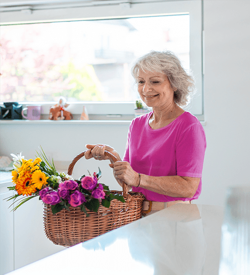 Mature woman in kitchen holding flowers