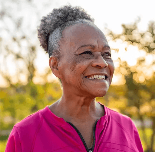 A mature woman wearing pink, smiling