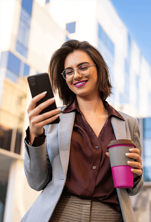 Woman holding a mobile and a pink coffee container