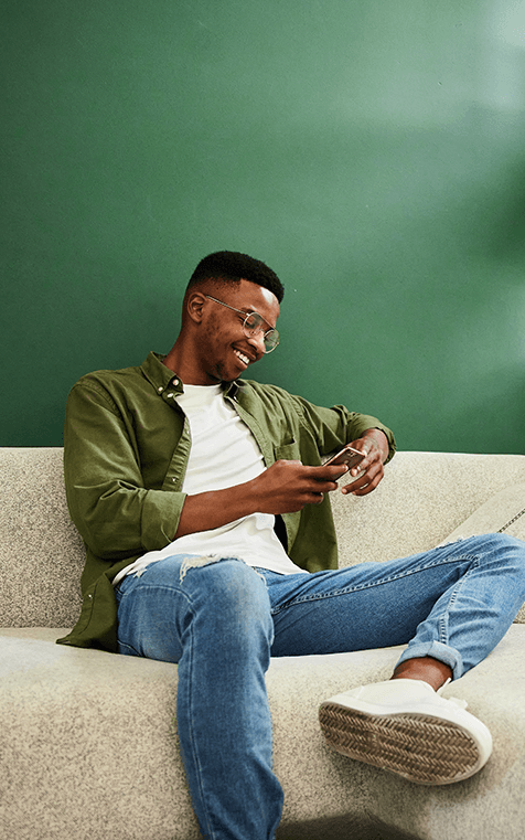 man relaxing on couch with mobile device